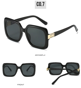 Detail of oversized square sunglasses featuring a golden rhinestone hinge on glossy black frame