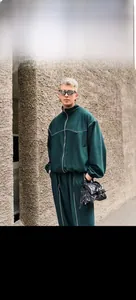 Detailed view of green men's sports tracksuit with white stitching and stylish mirrored sunglasses