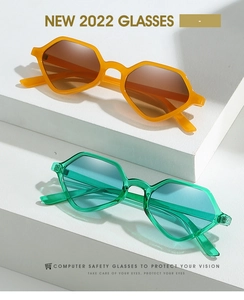 Close-up of geometric hexagonal sunglasses in solid orange and transparent green frames