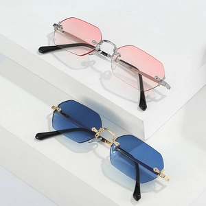 Frameless polygonal sunglasses with pink gradient and deep blue lenses on a white pedestal