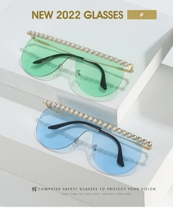 Detail view of oversized sunglasses featuring rhinestone trim and light blue/green lenses