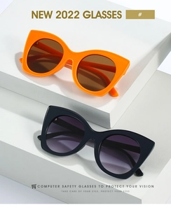 Detail of oversized cat-eye sunglasses in orange and black frames on white display