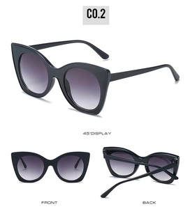 Detail view of oversized cat-eye sunglasses with thick black frames and purple gradient lenses