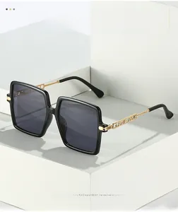 Detail of square oversized sunglasses with gold metal temples and love me engraving