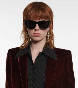 Close-up of stylish burgundy velvet blazer paired with dark cat-eye sunglasses on model