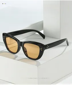 Detailed shot of black cat-eye sunglasses with yellow lenses and triple gold rivets