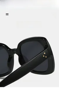 Detailed close-up of square sunglasses featuring triple gold rivets and sleek black finish