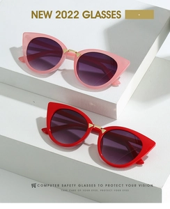 Detail of cat-eye sunglasses with gold bridge and purple gradient lenses on white display