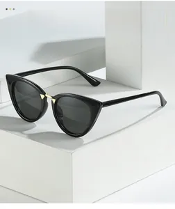 Close-up of cat-eye sunglasses with gold metal details on a white geometric platform