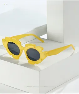 Detail of yellow flower-shaped sunglasses for kids with dark lenses on a white block