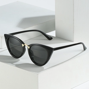 Fashion cat eye sunglasses with black glossy frames and gold metal bridge on a pedestal