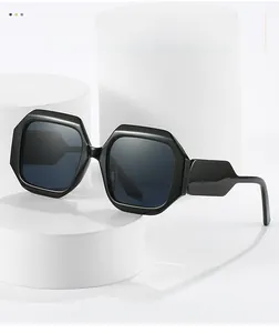 Close-up of black polygonal sunglasses with dark lenses on white cylindrical stands