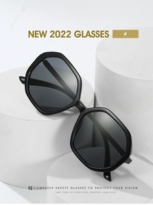 Detailed view of black polygonal sunglasses with dark grey lenses on white pedestals