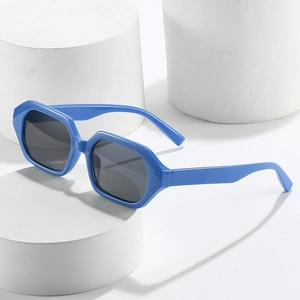 Chic polygonal bright blue sunglasses with dark grey lenses on white display stand