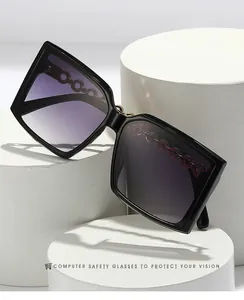 Detail of square black sunglasses with purple gradient lenses and metal chain temple design