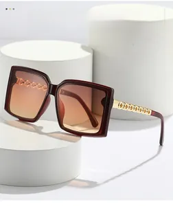 Detail of square oversized sunglasses featuring gradient lenses and gold chain temples