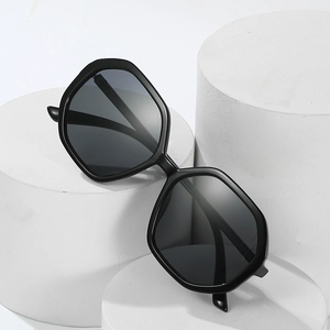 Chic oversized hexagonal sunglasses with black frames and dark lenses on white pedestals