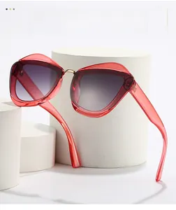 Detail of red translucent cat-eye sunglasses with purple gradient lenses and metal bridge
