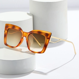 Retro amber cat eye sunglasses with gold cutout geometric metal temples on white pedestals