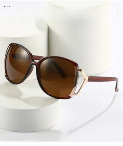 Detail of dark red oversized sunglasses with gold metal hollow design on the temples