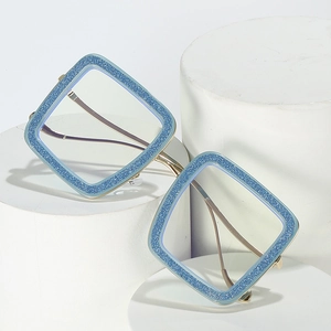 Blue glitter square frame glasses with gold metal temples on a minimalist white stone