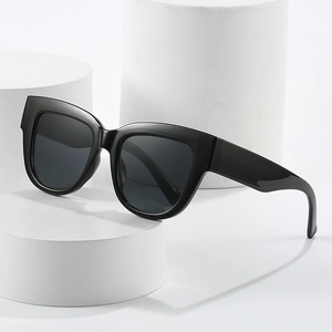 Lunettes de soleil œil de chat noires chics sur un présentoir blanc minimaliste