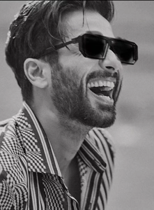 Close-up of oversized geometric black square sunglasses on a male model in black and white