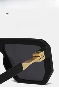 Detailed close-up of golden metal hinge on black chunky square frame sunglasses