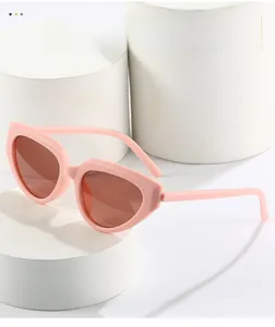 Detailed close-up of pink cat-eye sunglasses with brown lenses on a white pedestal