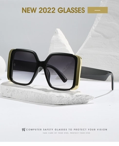 Detail of square sunglasses featuring golden metal accents on a white stone background