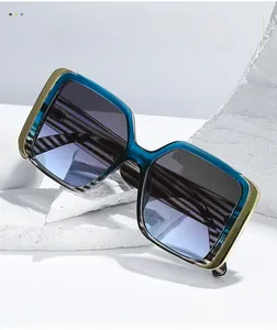 Detail view of square teal resin sunglasses with gold metal frame and gradient lenses