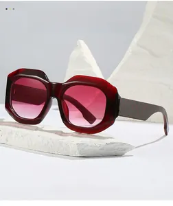 Detail of burgundy oversized geometric sunglasses with pink gradient lenses and checkered temple