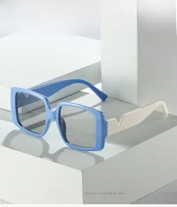 Detail of square blue sunglasses with cream white temples and V-shaped metal hardware
