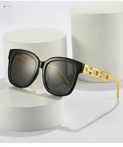 Detail shot of black oversized sunglasses with distinct gold chain style temples on display