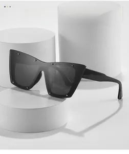 Detail view of black cat-eye sunglasses with silver stud rivets on white geometric props