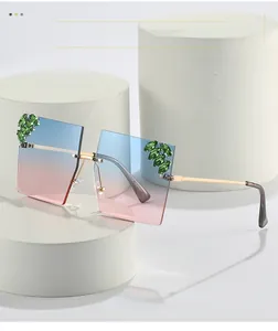 Detail of rimless sunglasses with blue-pink gradient lenses and green marquise rhinestones