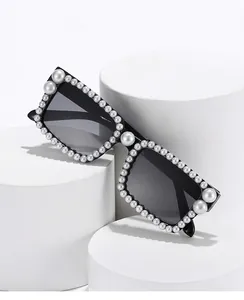 Schwarze quadratische Sonnenbrille mit weißen Perlen am Rahmen und grauen Gläsern