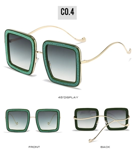 Detail view of square sunglasses with green glitter frames and golden wavy metal temples