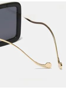 Detail of square sunglasses showing curved gold metal legs and ergonomic design