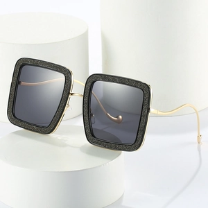 Oversized square sunglasses with gold metal frames and textured black glitter accents