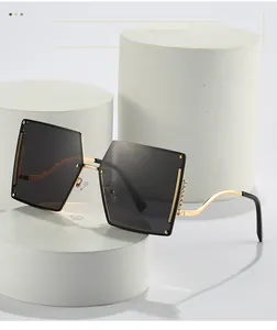 Close-up of frameless gradient sunglasses with gold wavy temples and rhinestone detail