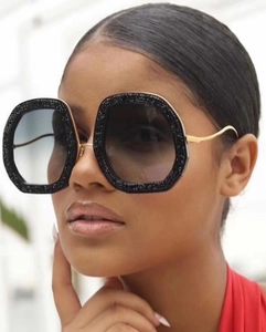Detail of glitter hexagonal sunglasses with dark gradient lenses and gold metal temples