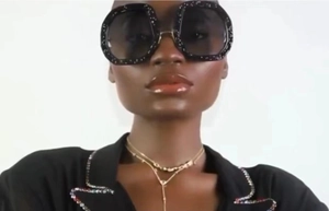 Close-up of stylish glitter frame oval sunglasses with black lenses on fashion model