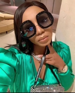 Close-up of oversized oval glitter sunglasses styled with crystal jewelry and green silk