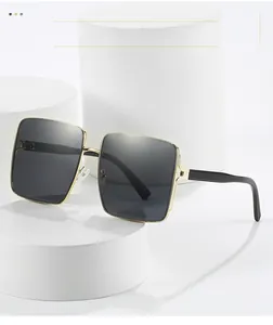Detailed view of square sunglasses with gold metal frames and black temples on white pedestal