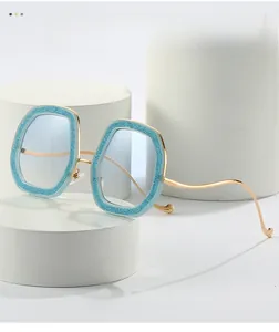 Detailed view of wavy gold metal temples and blue glitter on geometric sunglasses