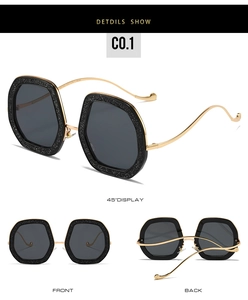 Detail view of hexagonal glitter sunglasses with wavy gold metal temples and dark lenses