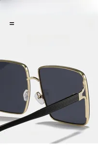Detailed macro view of textured gold metal temples and hinge on large square sunglasses