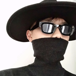 Close-up of square frame punk sunglasses styled with a black hat and high neck sweater