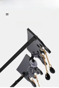 Détail de lunettes de soleil noires avec chaîne dorée et pendentif goutte sur la branche
